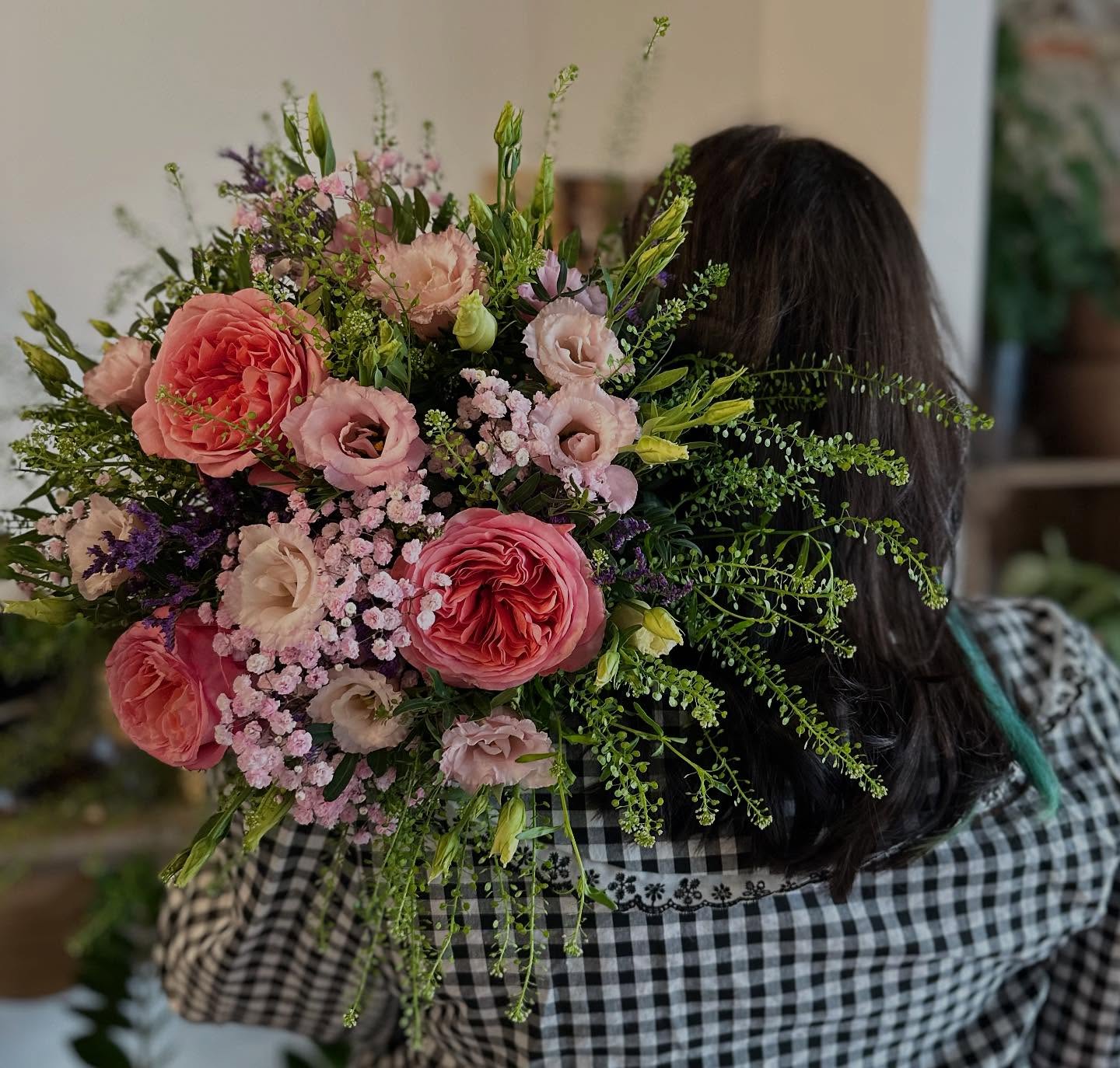 Bouquet de fleurs fraîches avec livraison à domicile Grand bouquet de fleurs fraîches aux tons roses et corail, composé de roses, lisianthus et gypsophile, présenté par une fleuriste. Disponible en livraison à domicile pour toutes vos occasions : anniversaire, mariage ou simple attention.